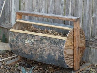 an old wooden barrel is sitting in the dirt near a fence and some wood planks