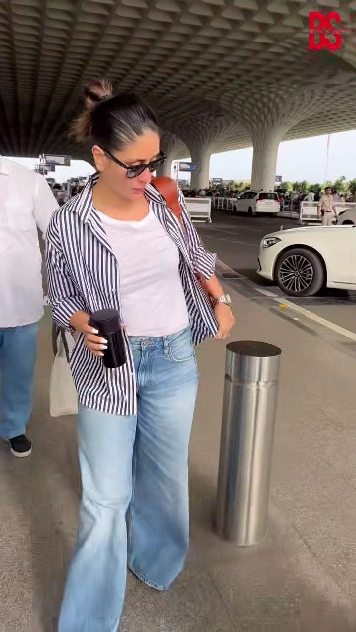 a woman is walking through an airport with her cell phone in her hand and wearing jeans