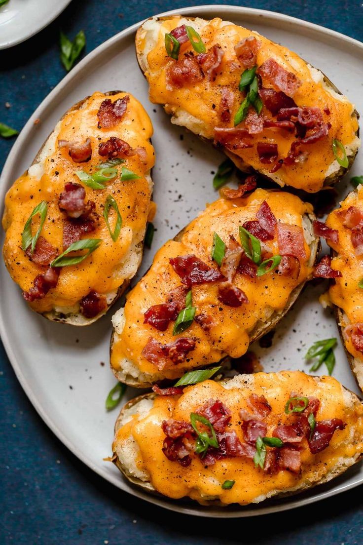 four pieces of bread with cheese and bacon on it sitting on a white platter