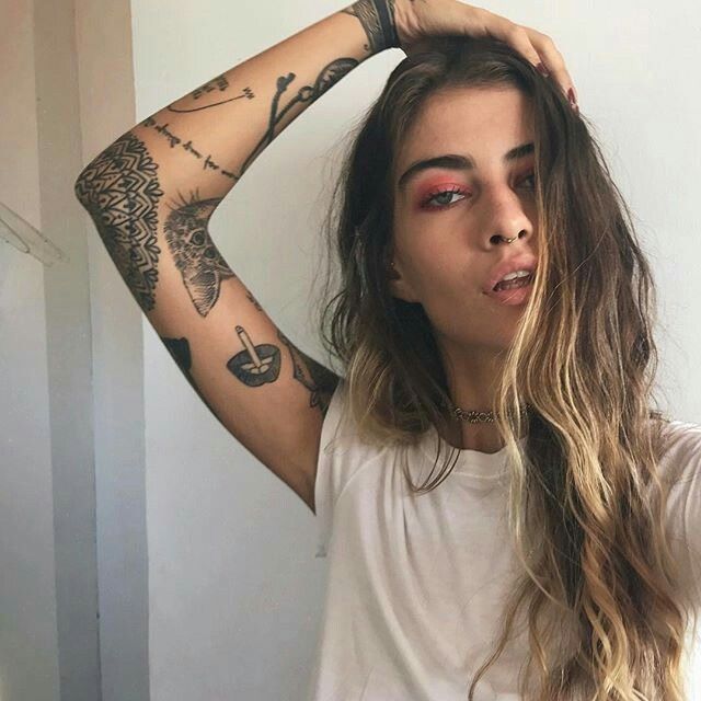 a woman with long hair and tattoos on her arms