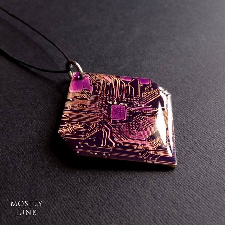 an electronic circuit board pendant is shown on a black surface with the words mostily junk written below it