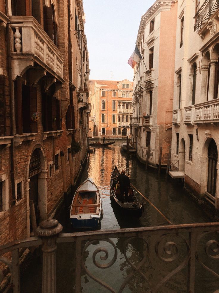 two boats are docked in the canal between buildings