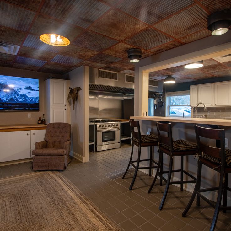 a kitchen with bar stools and a television mounted to the wall in front of it