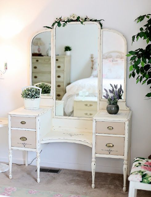 a white dresser with mirror and potted plant on it in front of a bed