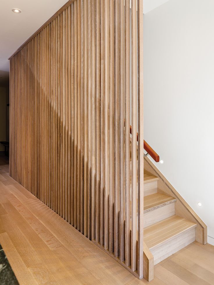 a wooden stair case next to a white wall