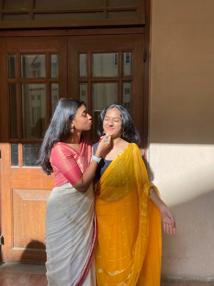 two women standing next to each other in front of a door