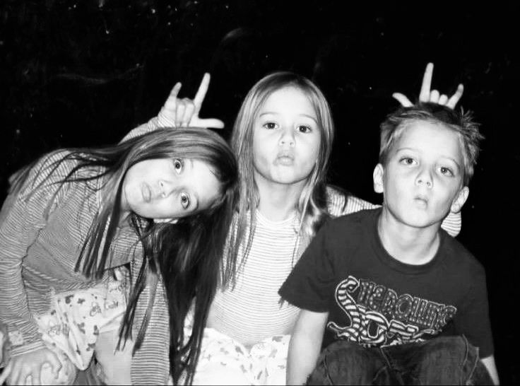 three young children sitting next to each other in front of a black and white photo