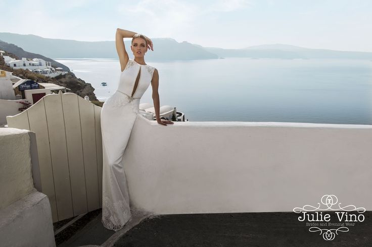 a woman in a white dress leaning against a wall with her arms behind her head