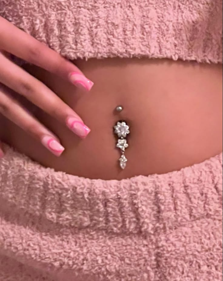 a woman's stomach with pink and white nail polishes on it, while wearing a belly ring