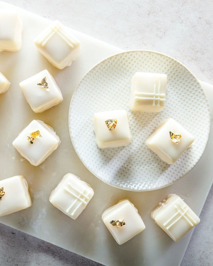 several pieces of white chocolate on a plate with some gold studs in the middle