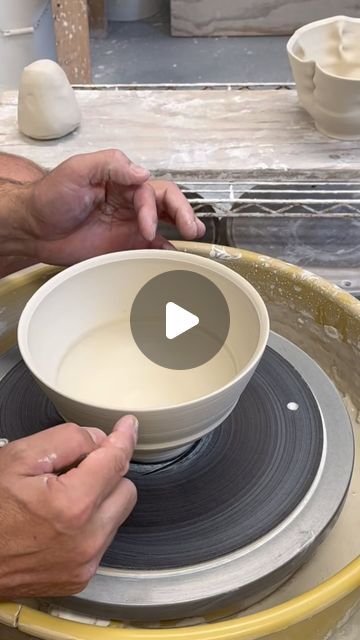 two hands are holding a bowl on top of some plates and making it look like they're working on something