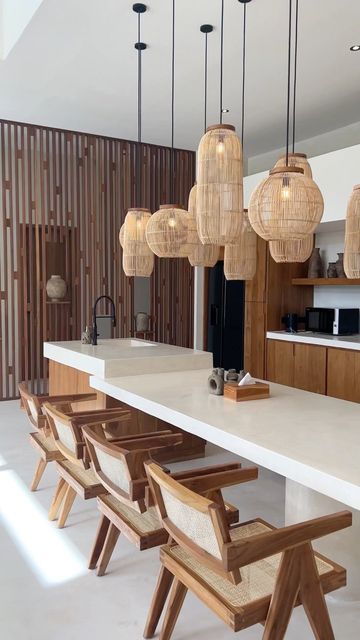 a long table with chairs and lights hanging from it's ceiling in a kitchen