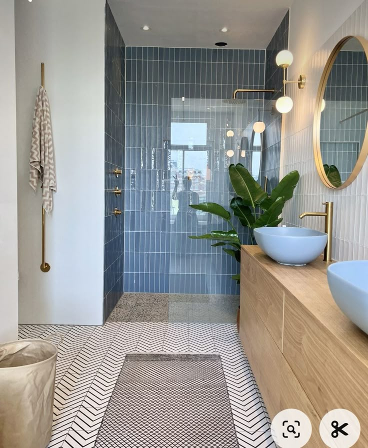 a modern bathroom with blue and white tiles on the floor, large plant in the corner