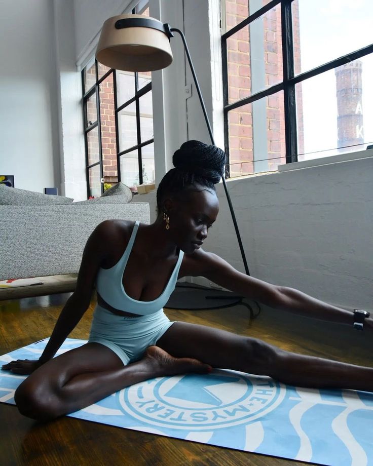 a woman sitting on a yoga mat in front of a window