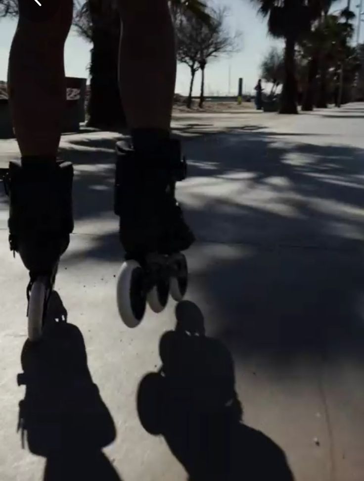 a person riding a skateboard down a street with palm trees in the back ground