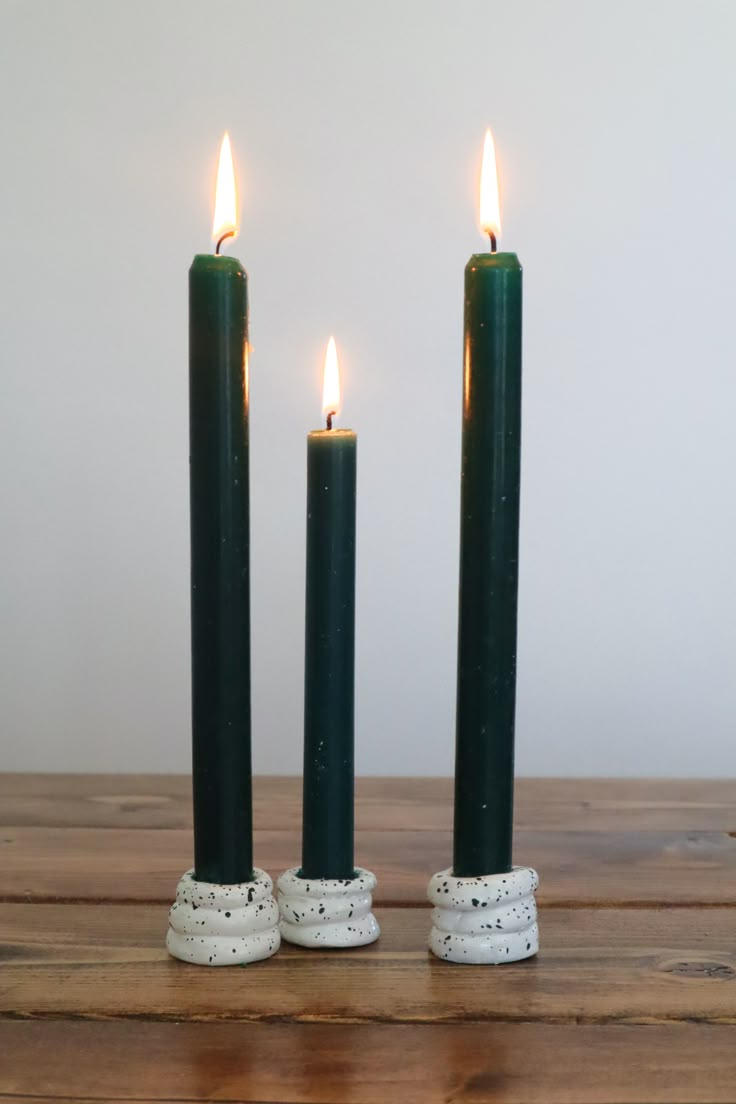 two black candles sitting on top of a wooden table