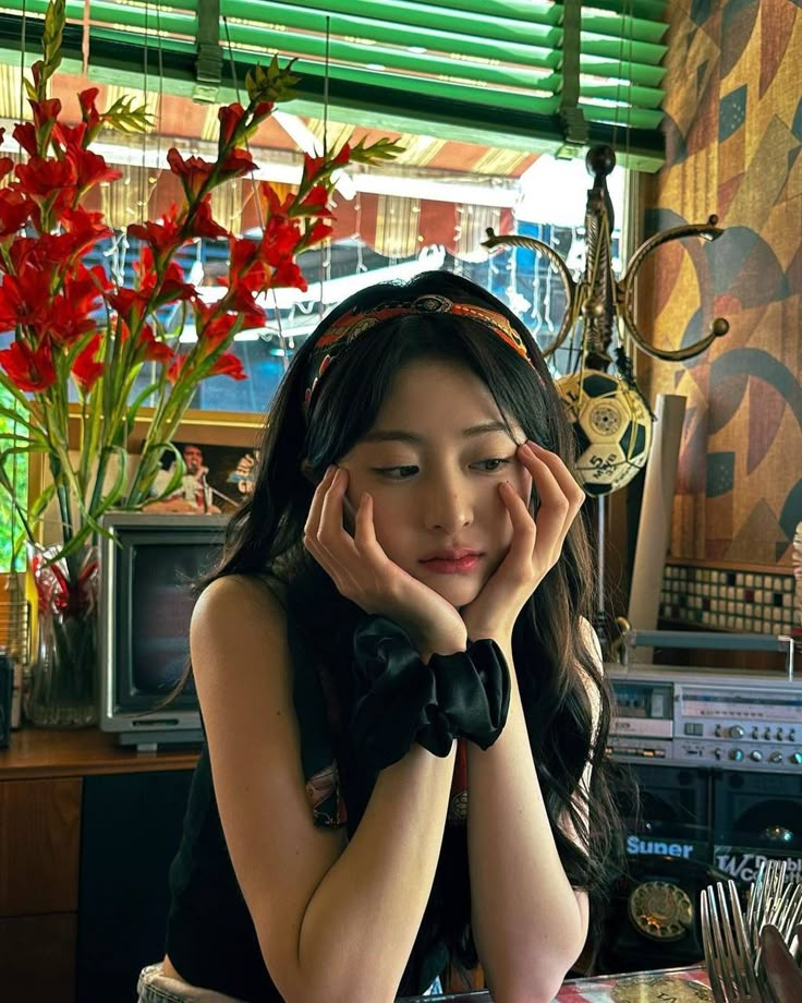 a woman sitting at a table with her hands on her face and looking away from the camera