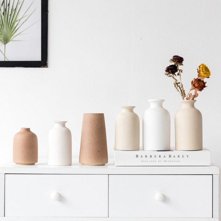 five white vases sitting on top of a dresser