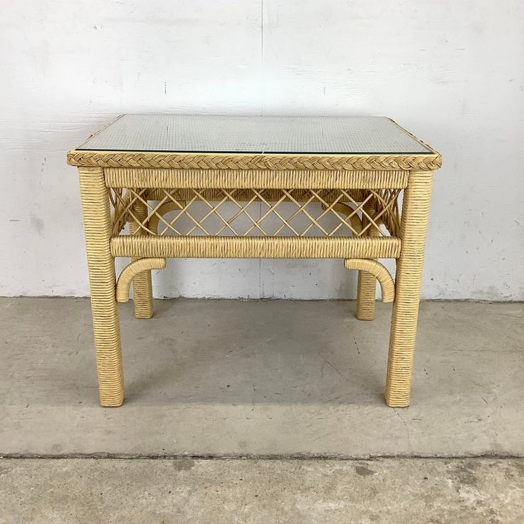 a wicker table with glass top on concrete floor