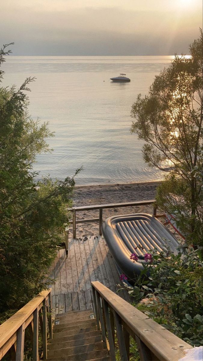 there is a boat on the water and stairs leading up to the beach with trees