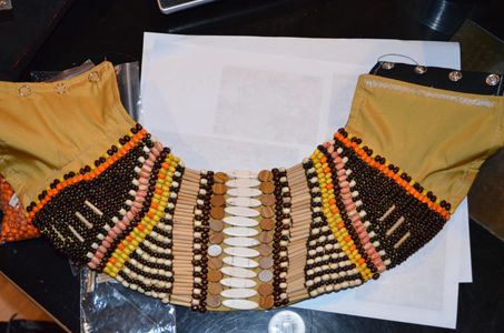 a brown and yellow necklace sitting on top of a table next to a laptop computer