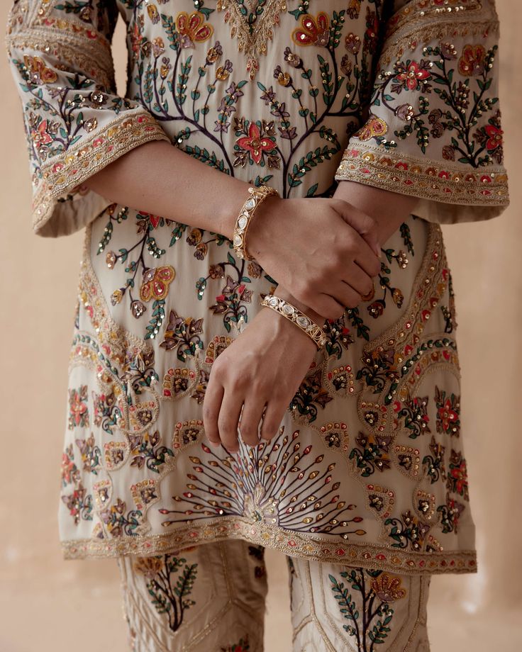 Editor's Note Introducing an elegant ivory kurta adorned with intricate floral thread embroidery, beautifully highlighted with various embellishments. This exquisite piece is paired with pants, creating a graceful and sophisticated ensemble perfect for special occasions or cultural events. The delicate embroidery and thoughtful embellishments add a touch of charm, making this outfit a stunning choice for those who appreciate timeless beauty and style. Fabric: Pure georgette Color: Ivory Componen Luxury Embroidered Chanderi Fabric For Festivals, Luxury Chanderi Sets With Gold Embroidery, Luxury Traditional Kurta With Motifs, Luxury Dola Silk Traditional Wear With Floral Embroidery, Luxury Art Silk Traditional Wear With Resham Embroidery, Luxury Silk Traditional Wear With Intricate Embroidery, Luxury Floral Embroidered Traditional Wear In Dola Silk, Luxury Traditional Pants With Intricate Embroidery, Luxury Chanderi Embroidered Top With Resham Embroidery