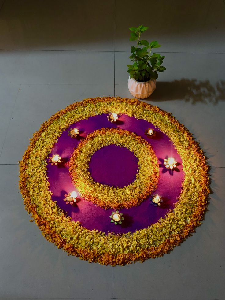 a purple and yellow flower arrangement on top of a white floor with a potted plant next to it