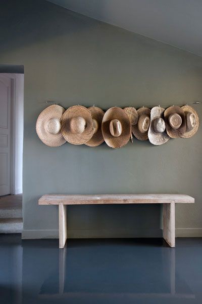 hats are hanging on the wall next to a bench with a wooden bench underneath it