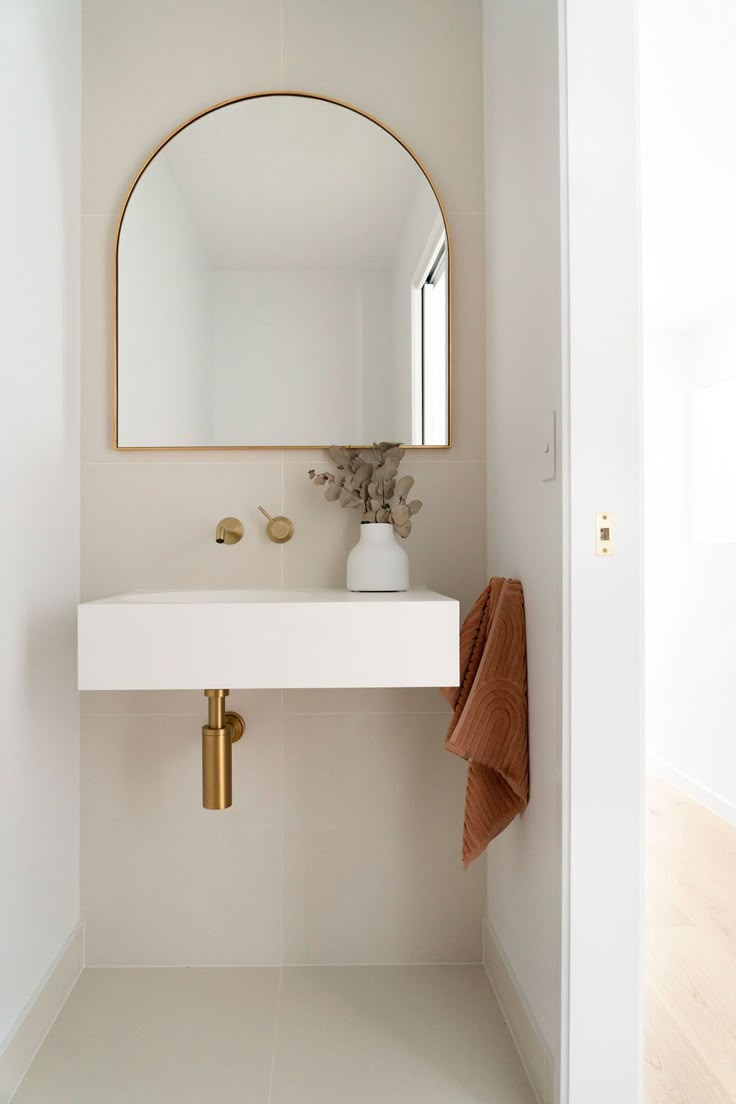 a bathroom with a sink, mirror and gold faucet on the wall above it