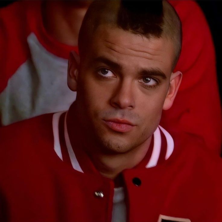 a close up of a person wearing a red jacket and looking at the camera with an intense look on his face