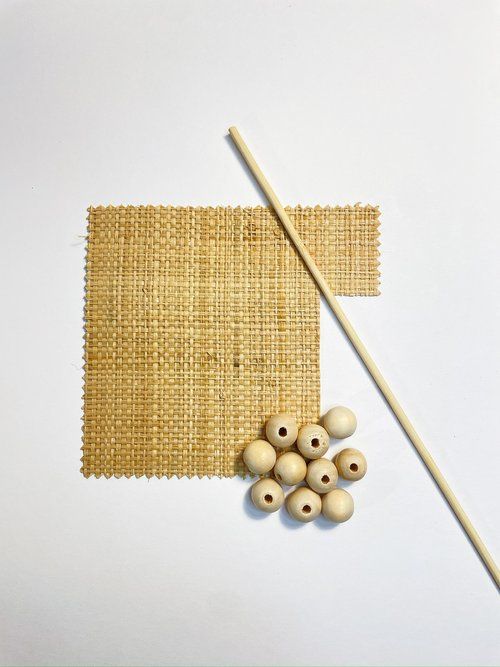 two chopsticks and some wood beads on a white surface with a piece of burlap