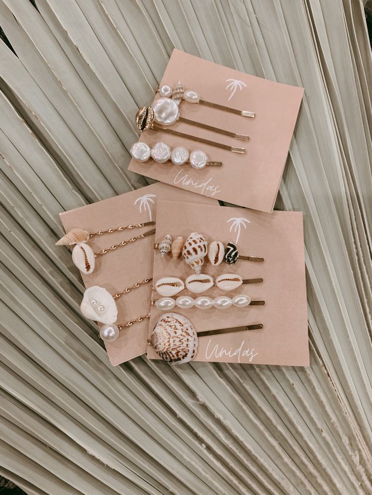 three pieces of paper with shells on them sitting next to each other in front of a palm tree