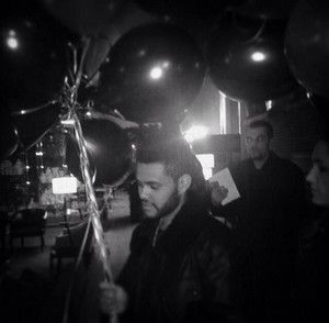 a black and white photo of a man with balloons in the air at a party