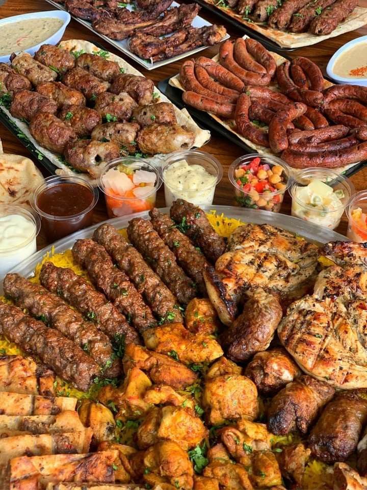 an assortment of meats and other food items on a wooden table with utensils