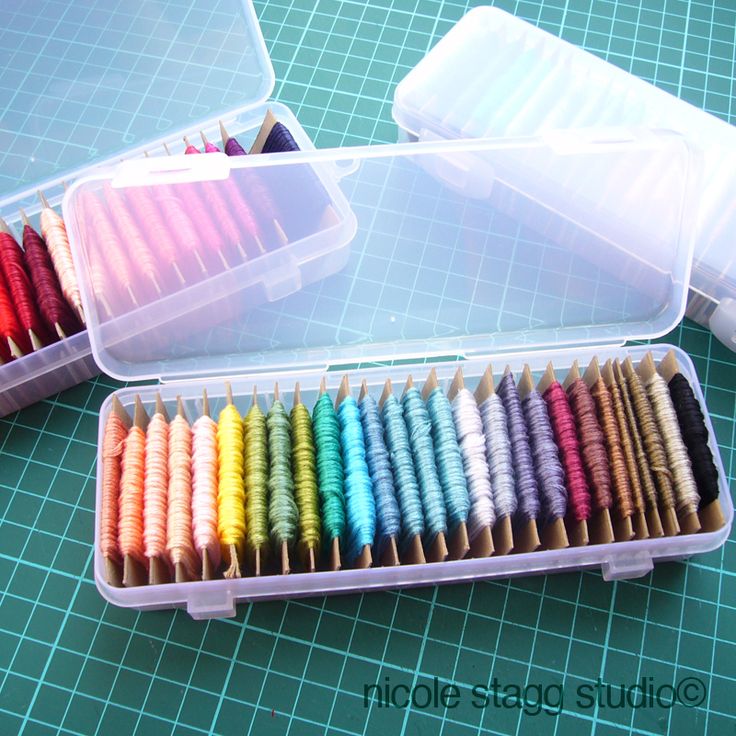 two plastic containers filled with different colored toothbrushes on top of a green table