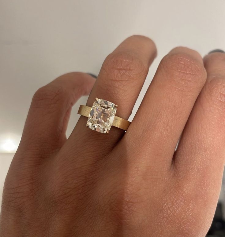 a person's hand with a ring on it and a diamond in the middle