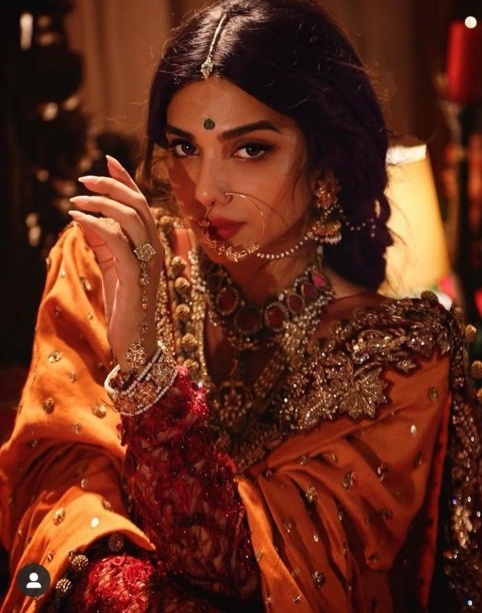 a woman in an orange outfit with jewelry on her face