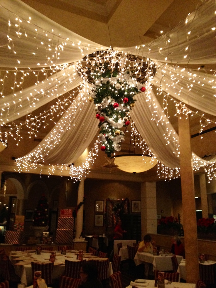 the inside of a restaurant decorated for christmas with lights and drapes hanging from the ceiling