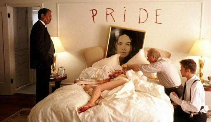 two men and a woman in bed with the word pride written on the wall behind them