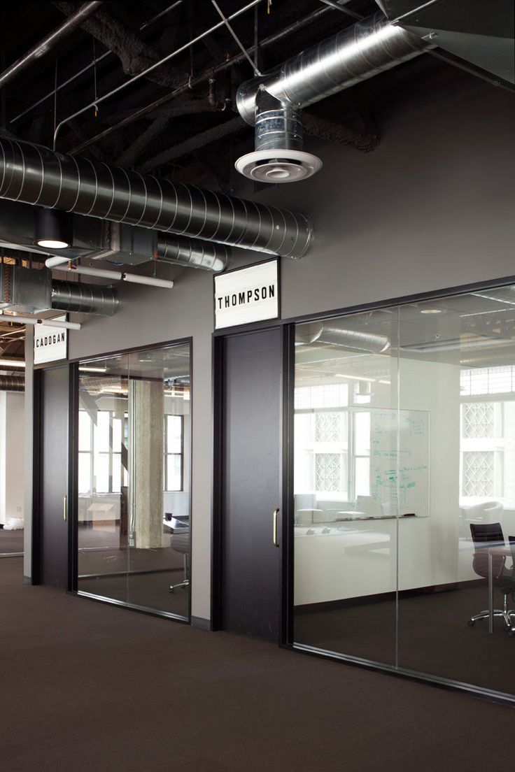 an empty office with glass walls and black doors