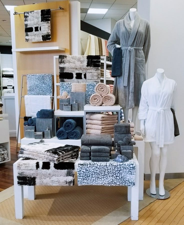 a display in a store filled with lots of towels and bathrobe items on top of tables