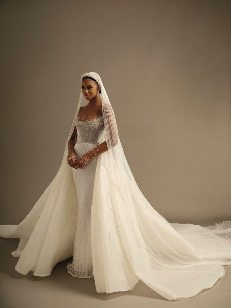 a woman in a white wedding gown and veil posing for the camera with her hands on her hips