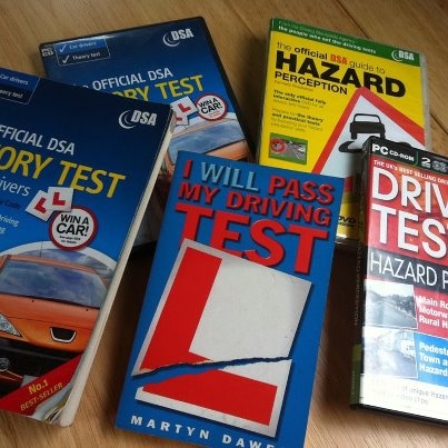 four books on driving test sitting on top of a wooden table