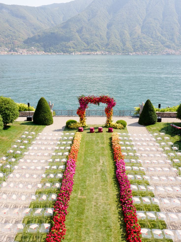 an outdoor ceremony set up with flowers on the lawn and water in the background,