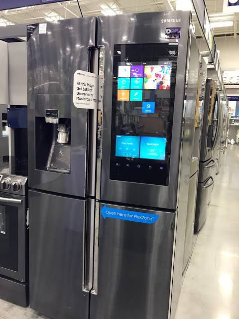 a stainless steel refrigerator in a store with windows on the front and side doors open