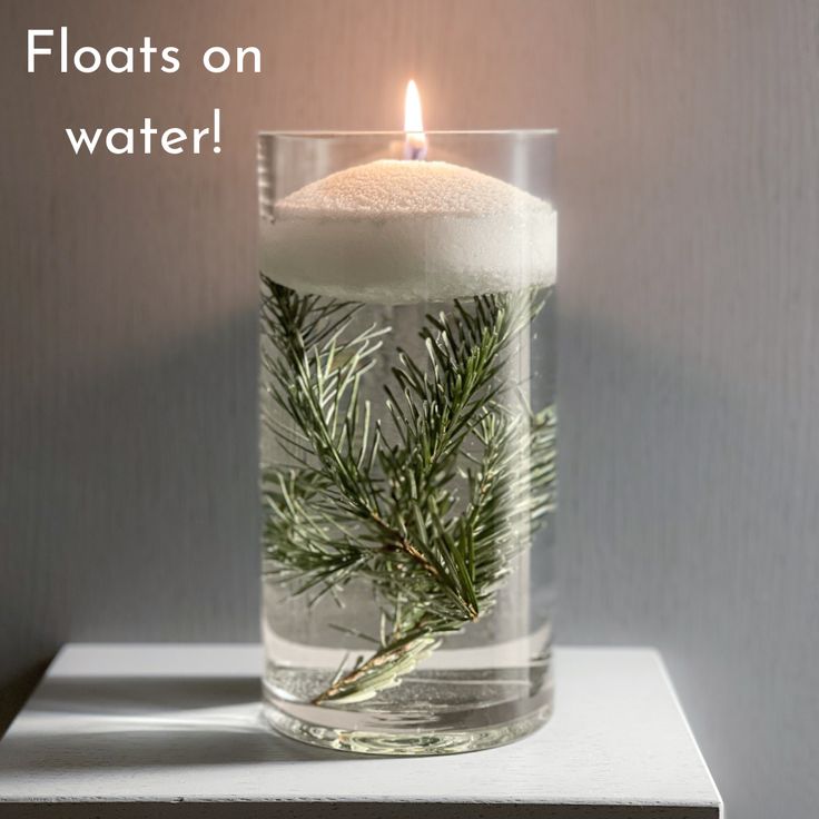 a candle that is inside of a glass vase with water and pine branches in it