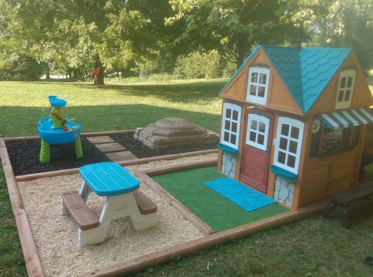 there is a small play area in the yard with a house and picnic table on it