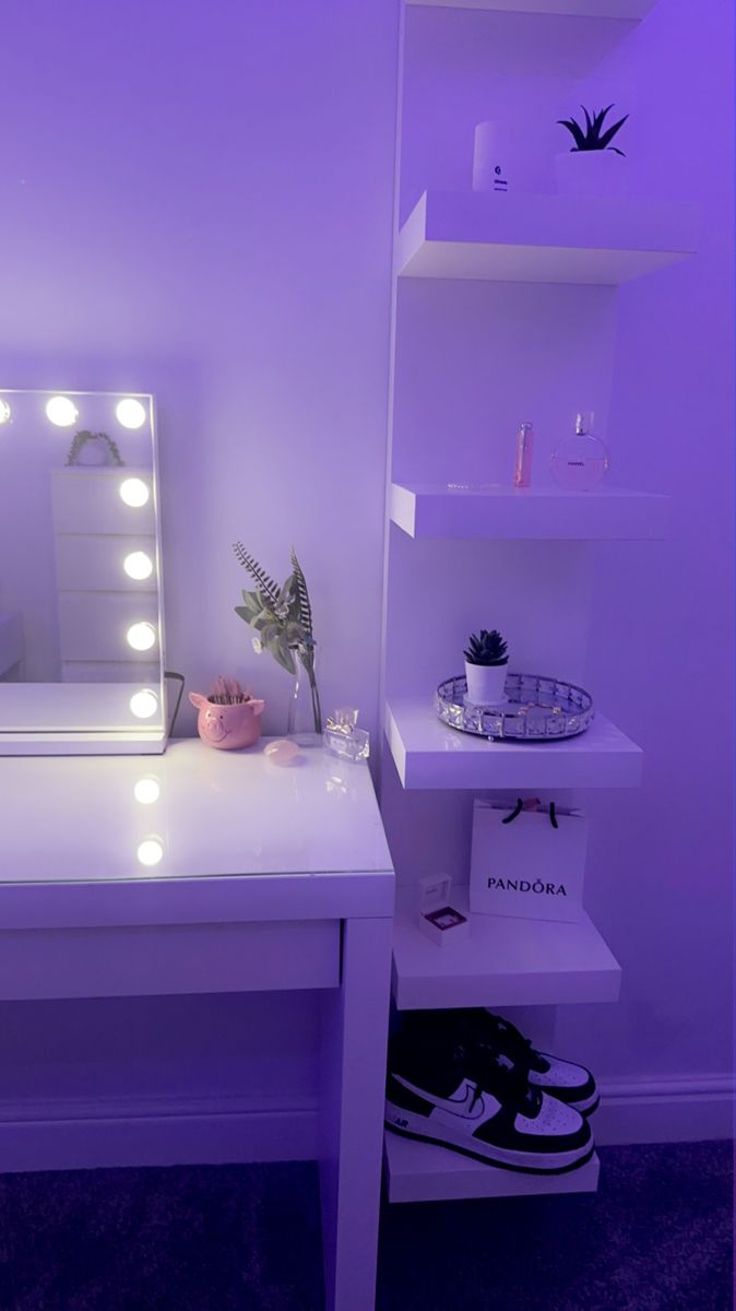 a white desk topped with a mirror next to a shelf filled with plants and lights