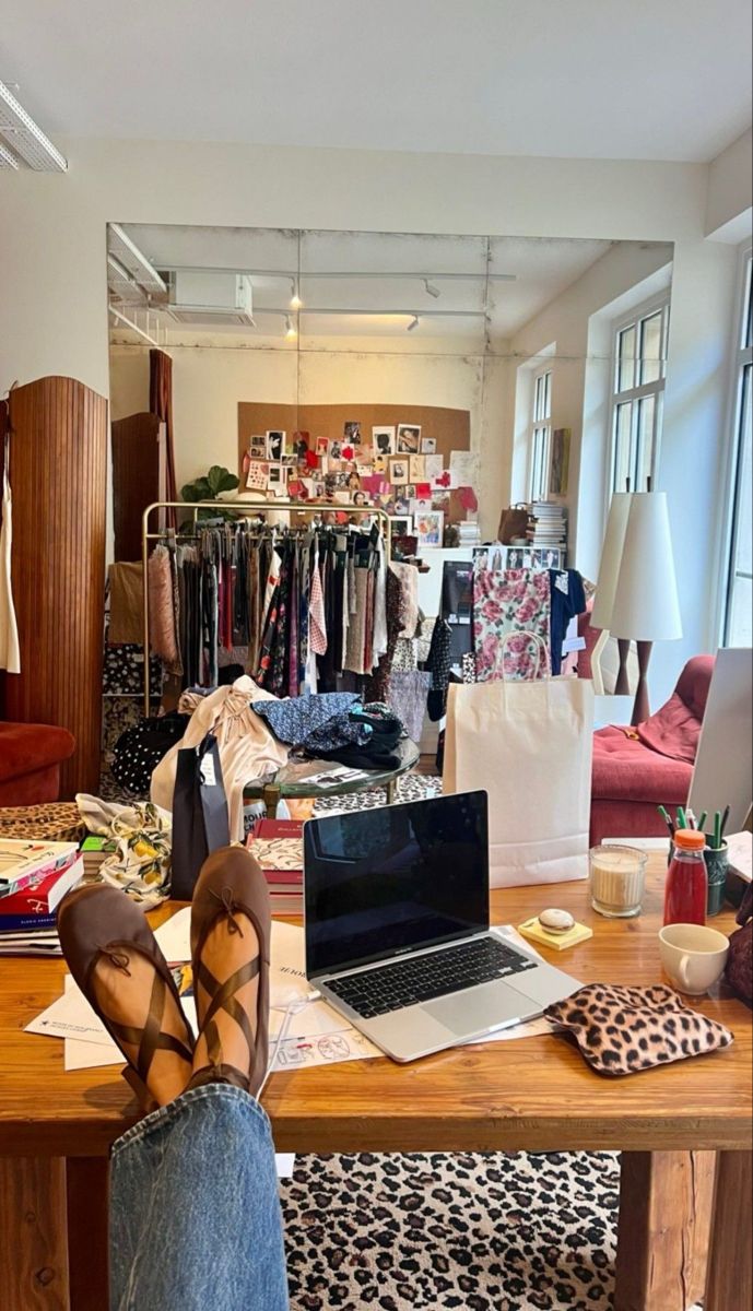 a person's feet resting on a table in front of a laptop and clothes