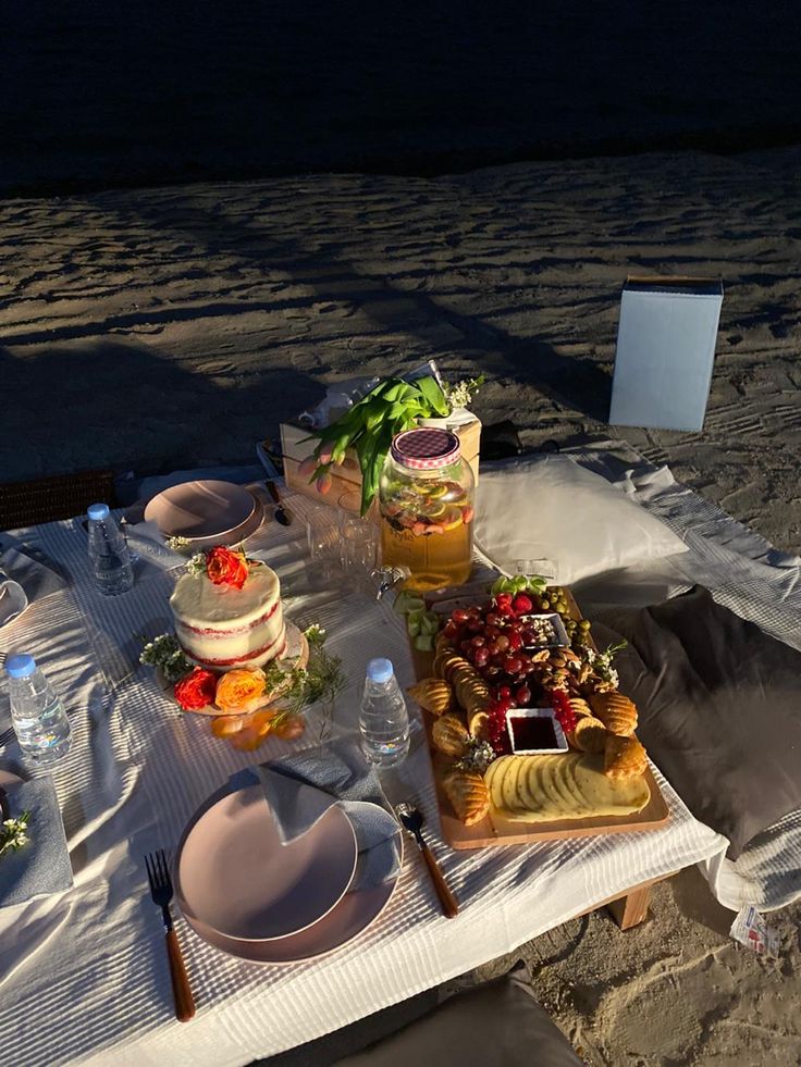 a table set up on the beach with food and drinks